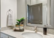 Thumbnail 27 of 34 - A bathroom with a sink, mirror, and a plant.
