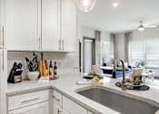 Thumbnail 21 of 34 - A modern kitchen with white cabinets and a marble countertop.
