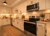 Thumbnail 4 of 33 - A modern kitchen with white cabinets and stainless steel appliances.