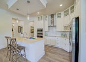 Thumbnail 36 of 53 - A kitchen with a white island and wooden floors.