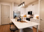Thumbnail 19 of 40 - A modern kitchen with a white island and stools.