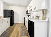 Thumbnail 3 of 15 - Harrisonburg, VA, Pet-Friendly Student Apartments - The Mill - A Clean, Modern Kitchen With White Cabinetry, White Countertops, And Contrasting Black Appliances.