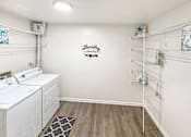 Thumbnail 12 of 15 - A laundry room with a washer and dryer, a rug, and a wall decal.
