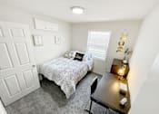 Thumbnail 8 of 15 - Harrisonburg, VA, Fully Furnished Student Apartments - The Mill - A Bright, Minimalist Bedroom With A Rustic Wood Dresser, A Large Window, And A Bed With Neutral-Toned Linens.