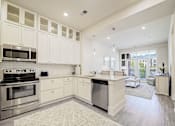 Thumbnail 23 of 53 - A kitchen with white cabinets and stainless steel appliances.
