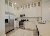 Thumbnail 22 of 53 - A kitchen with white cabinets and appliances.