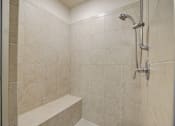 Thumbnail 31 of 53 - A shower area with a bench and a shower head.