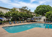 Thumbnail 11 of 28 - A swimming pool surrounded by chairs and trees.
