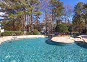 Thumbnail 36 of 44 - a swimming pool with a patio and trees in the background