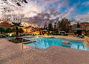 Thumbnail 29 of 38 - A swimming pool surrounded by a concrete patio and trees.