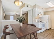 Thumbnail 2 of 13 - a dining room with a wooden table and a kitchen with white appliances