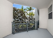 Thumbnail 14 of 35 - A balcony with a metal railing overlooking a lush green area.