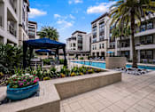 Thumbnail 31 of 42 - A pool area with a blue canopy and a large planter with pink flowers.