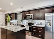 Thumbnail 7 of 42 - A modern kitchen with dark wood cabinets and stainless steel appliances.