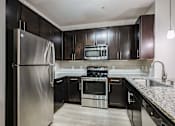 Thumbnail 18 of 42 - A kitchen with a stainless steel refrigerator and black cabinets.