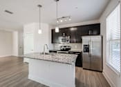 Thumbnail 17 of 42 - A modern kitchen with a granite countertop and stainless steel appliances.