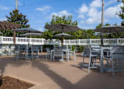 Thumbnail 17 of 31 - A patio with tables and chairs under umbrellas.