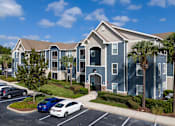 Thumbnail 1 of 31 - A car is parked in a parking lot in front of a building.