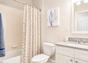 Thumbnail 6 of 31 - A white toilet sits next to a bathtub in a bathroom.
