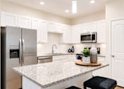 Thumbnail 2 of 31 - A kitchen with granite countertops and stainless steel appliances.