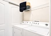 Thumbnail 8 of 31 - A white washing machine and dryer in a small laundry room.