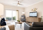 Thumbnail 4 of 31 - A living room with a couch, a chair, a coffee table, and a television displaying the text "The North Beach".