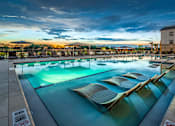 Thumbnail 16 of 45 - Luxury Apartments In Jacksonville, FL, With In-Unit Washer And Dryer - The Clarke At Kendall Town - A Large Swimming Pool At Sunset Featuring In-Water Lounge Chairs.