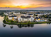 Thumbnail 38 of 45 - A serene landscape with a building reflected in a body of water during sunset.
