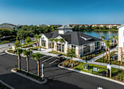 Thumbnail 32 of 45 - A large building with a black roof is surrounded by a parking lot and palm trees.