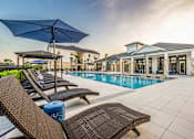 Thumbnail 15 of 45 - A poolside area with lounge chairs and umbrellas.