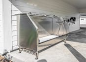 Thumbnail 29 of 45 - A large metal container with wheels and a handle is placed on a concrete floor.