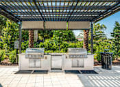 Thumbnail 18 of 45 - Two grills are under a roof in a sunny outdoor area.