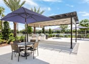Thumbnail 19 of 45 - A patio with a table and chairs under a purple umbrella.