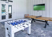 Thumbnail 28 of 48 - A foosball table is in the middle of a room with a bench and a television.