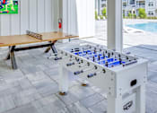 Thumbnail 29 of 48 - A foosball table is in the middle of a room with a pool table and a bench.