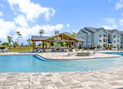 Thumbnail 30 of 48 - A large swimming pool with a pavilion and a building in the background.