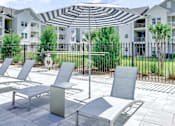 Thumbnail 36 of 48 - A patio with chairs and a table with a striped umbrella over it.