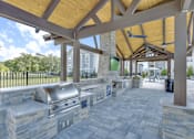 Thumbnail 31 of 48 - A covered outdoor area with a grill and picnic tables.
