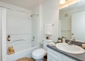 Thumbnail 26 of 28 - A white bathroom with a toilet, sink, and bathtub.