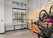 Thumbnail 24 of 33 - A bicycle is parked in a room with a bench and a window.