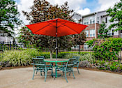Thumbnail 28 of 29 - A red umbrella is in front of a green table.