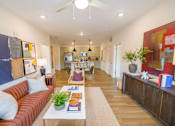 Thumbnail 3 of 40 - One-Bedroom Apartments in Athens, GA - Classic City Flats - Living Room With Wood-Style Flooring, Ceiling Fan, Open Floor Plan, A Couch, Rug, And Wall Arts.