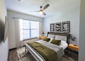 Thumbnail 5 of 46 - A bedroom with a bed, a ceiling fan, and a television.