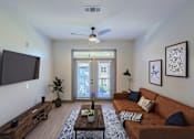 Thumbnail 4 of 46 - A living room with a brown couch and a flat screen TV mounted on the wall.