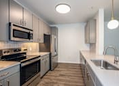 Thumbnail 11 of 35 - A kitchen with a stove top oven, microwave, and refrigerator.