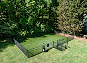 Thumbnail 24 of 33 - A black fenced area with a blue sign in the middle of a grassy field.