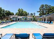 Thumbnail 27 of 33 - A large swimming pool surrounded by lounge chairs and trees.