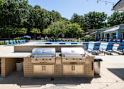 Thumbnail 32 of 33 - A barbecue grill is in the middle of a pool area.