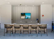 Thumbnail 31 of 33 - A television is mounted on a wall above a counter with four chairs in front of it.