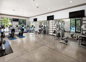 Thumbnail 6 of 33 - A gym with a variety of equipment including treadmills, weights, and exercise machines.